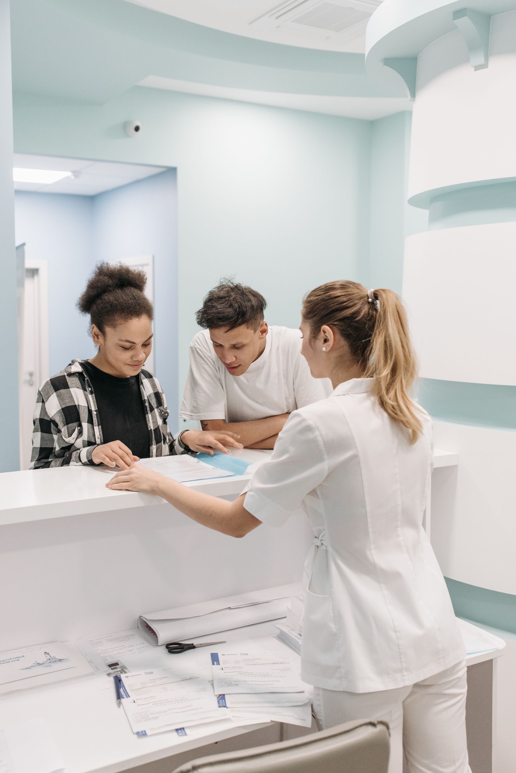 Clinic staff and patients reviewing paperwork at a bright front desk