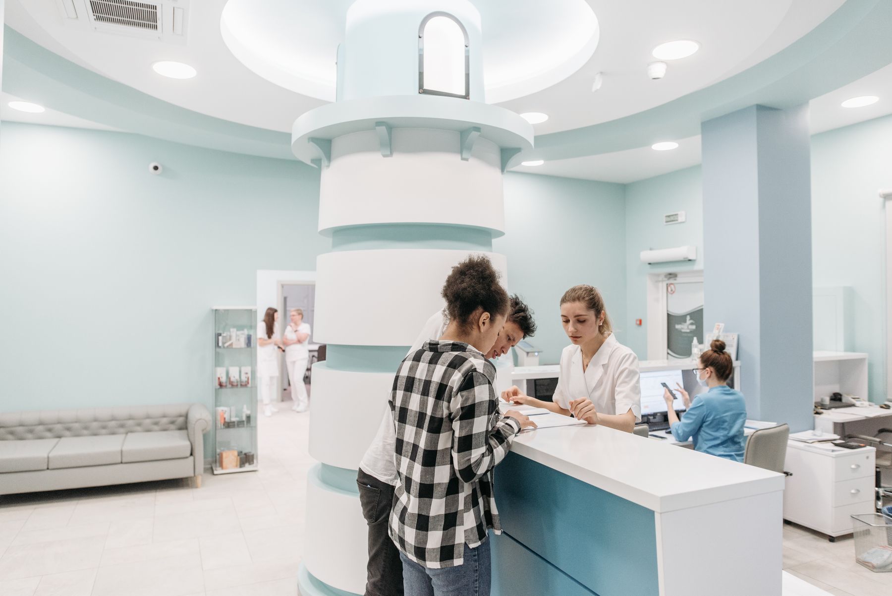 Modern clinic reception with staff at computers checking in a patient
